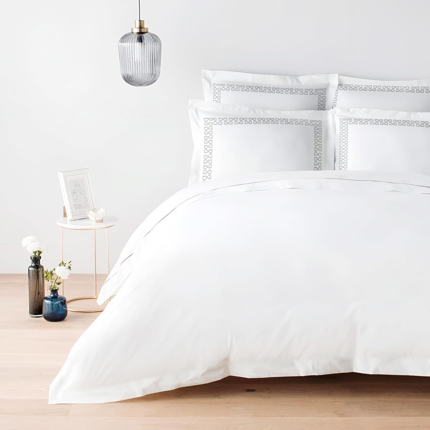 White bedding set with decorative pillows on a bed in a bedroom setting.